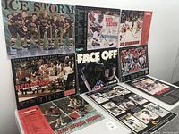 Photo of nine signed collegiate sports posters featuring Boston University hockey, baseball, and football teams with visible autographs.
