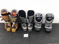 Three pairs of ski boots side by side: orange, silver, and blue.