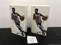 Pair of sealed Steph Curry Motion Masterpiece Series 1 figurine boxes with front artwork showing action pose of Steph Curry playing basketball.