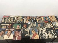 Wide view of multiple vintage magazine photo cutouts showing various male actors in black and white and color photographs.