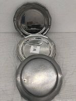 Side by side view of vintage metal plates showing front reflective surface and scalloped edge design.