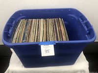 Blue plastic tub filled with vertically standing vinyl records, showing the extent of the collection.