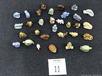 Top view of the full set of Wade miniature ceramic figurines showing various shapes and colors arranged in rows on a black surface.