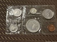 Five coins sealed in clear plastic packaging showing the 1967 Canadian Centennial coin set with silver dollar and smaller coins.