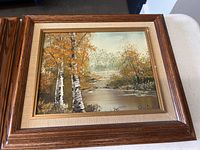 Framed painting visible with fall foliage and birch trees by a river