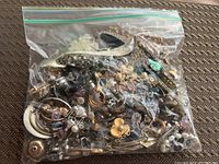 Plastic bag filled with various mixed jewelry pieces showing different metal tones, styles, and shapes.