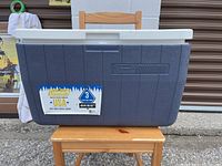 Closed Coleman cooler showing exterior, blue body, and white lid with Coleman logo and ice retention sticker.