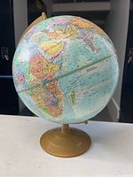 World globe showing Africa, parts of Europe, Asia, and surrounding ocean areas on a gold-colored metal base