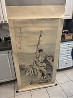Photo of large 7.5 feet Japanese scroll showing traditional figure, dogs, birds, calligraphy, and seals, rolled out and leaning against kitchen cabinets.