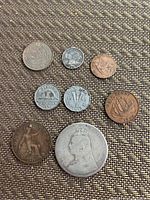 Photo showing eight mixed old coins of different metal types and sizes including an 1889 Queen Victoria silver coin and Canadian coins from 1945, 1954, 1964, 1917, 1916, and others.