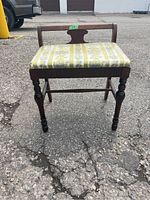 Front view of wood frame piano stool with upholstered seat and carved legs showing overall condition and style.
