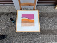 Top view of the framed abstract print showing pink, orange, beige curved bands with light wood frame and white mat.