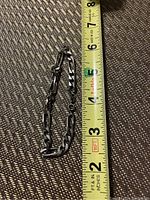 Photo of the sterling silver chain bracelet next to a measuring tape showing a length of approximately 7 inches.