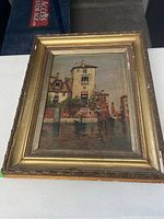 Front view of oil painting showing Venetian canal with buildings and boats, with ornate gold frame.