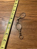Folding glasses folded closed next to measuring tape showing about 6 inches in length.