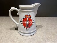 Front side of ceramic Coca Cola pitcher showing bottle image and checkered pattern