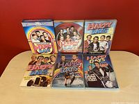 Six DVD cases of Happy Days TV series seasons displayed on a red background.