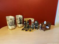 Harry Potter toys including two sealed action figure packages of Dumbledore and Snape, loose character figurines like Harry, Hermione, and Professor Lupin, an archway playset piece, wooden bed frame, and miniature framed portraits.