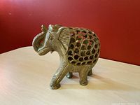 Front and side view showing the whole carved soapstone elephant with trunk up and intricate openwork sides.