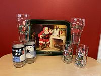 Front view showing vintage Coca Cola tray with Santa Claus and six themed glasses including polar bear, nutcracker, and Coca Cola holiday designs.
