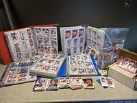 Several large binders open to display hockey trading cards, with loose cards spread on the table and in plastic bags.