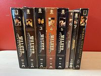 Front view of all eight Walker Texas Ranger DVD season sets arranged vertically showing spine artwork with Chuck Norris' image and season numbering.