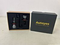 Autoyes branded packaging box with two LED headlight bulbs visible inside black foam insert.