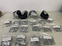 Four black castor wheels with metal brackets alongside multiple sealed bags of metal shear pins arranged on a flat surface