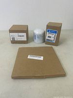 Three boxed items on a flat surface: two small boxes and one sealed white cylindrical filter wrapped in plastic, labeled Donaldson P550162.
