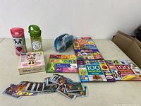 Full view of all items in the lot including water bottles, puzzle, books, stickers, and baby spout.