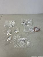 Several individually packaged spools of jewelry wire, with white labels and barcodes visible, arranged on a surface.