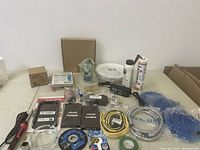 Full lot including various cables, gloves, spray cans, electrical accessories, and hardware on a white surface