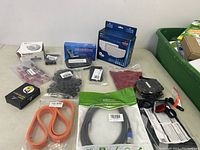 Overall lot view showing multiple electronics accessories and components on table