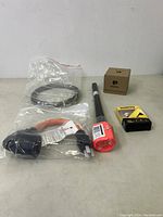 Five various new items grouped on table: power cable adapter, coiled black cable, black wires bundle, small cardboard box, small yellow Avatto box.