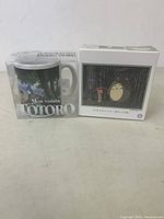 Front view of the two boxed items: the ceramic mug and the Totoro figurine.