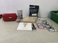 Photo showing all items included in womans lot such as red bag, beige elbow sleeves, resistance bands, boxed items, and small beauty tools in bags.
