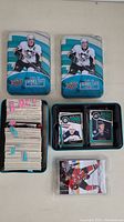 Two blue and white metal tins from 2011-12 Upper Deck Series Two containing stacks of hockey cards. One tin is open showing cards; the other is closed.