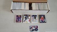Wide view showing a large lot of over 600 hockey cards in two long boxes with some loose cards in front, including a goalie card.