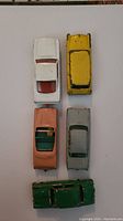 Top-down view of five vintage Lesney Matchbox cars in various colors showing wear and paint chipping.