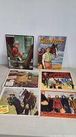 Set of six western movie posters including Gene Autry titles and others, plus coloring book cover and puzzle box.