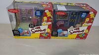 Two boxed Intelli-Tronic Simpsons toys side by side with visible packaging wear.