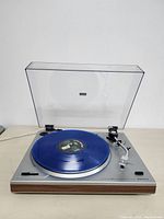 Vintage SANYO TP 1005 turntable with blue vinyl record playing, dust cover lifted showing details