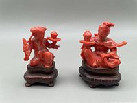 Front view of both red coral carvings on wooden bases