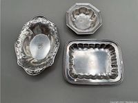 Three small sterling silver dishes shown together on a flat surface.