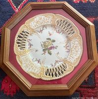 Framed KPM Berlin porcelain plate in octagonal wooden frame with red velvet backing.