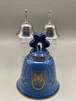 Photo showing two silver-colored metal bells behind the blue Bing & Grondahl porcelain bell.