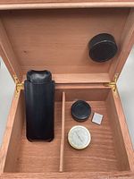 Open humidor showing interior with divider, black leather cigar case, humidifier, hygrometer, and humidity control packet.