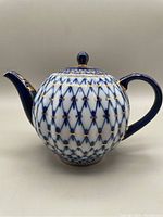 Front profile view showing spherical body, spout, handle and lattice pattern.