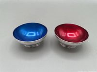 Pair of vintage enamelled salt cellars showing interior color and silver plated exterior.