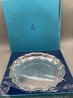 Photo showing the silver plated tray inside a blue box, with clear shrink wrap around the tray. The box lid showing Birks logo and brand.